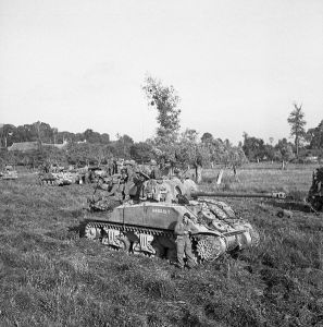 British_infantry_and_Sherman_tanks_wait_to_advance_at_the_start_of_Operation_Goodwood_Normandy_18_July_1944._B7513
